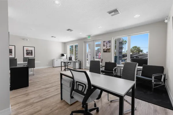 a kitchen with stainless steel appliances a refrigerator a stove top oven a dining table and chairs with wooden floor