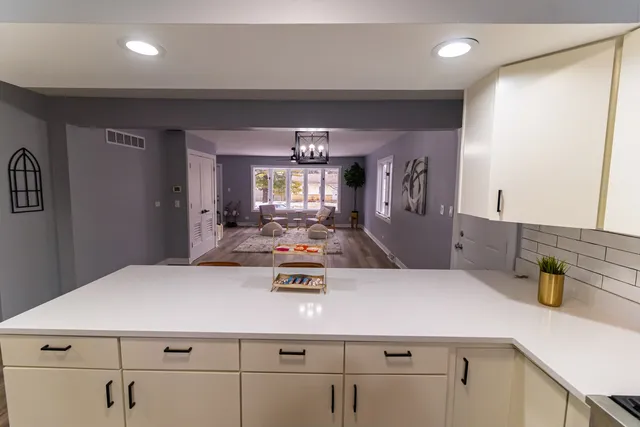a kitchen with kitchen island a stove and white cabinets