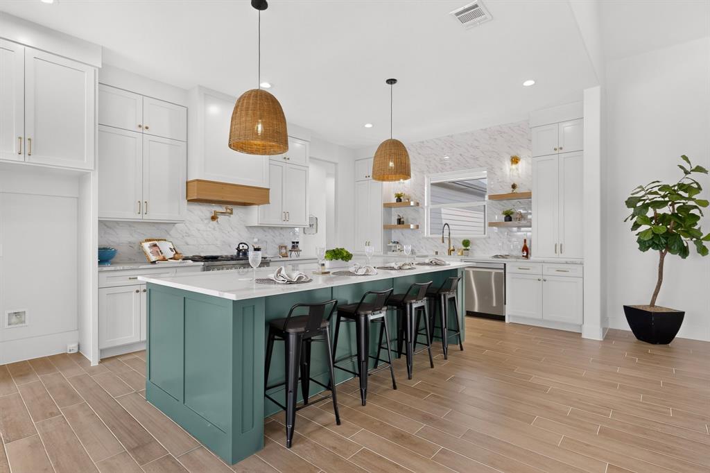 5410 Sunset Road Caddo Mills, TX 75135 - Photo 14 of 40 Kitchen featuring a large island with seating, white shaker-style cabinetry, wood-finish flooring, and stainless steel appliances