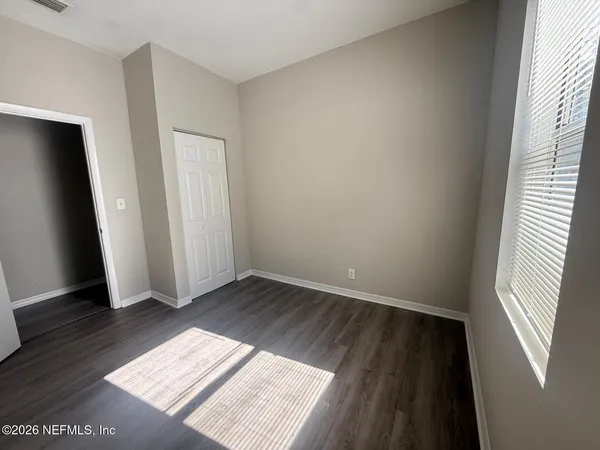an empty room with wooden floor and windows