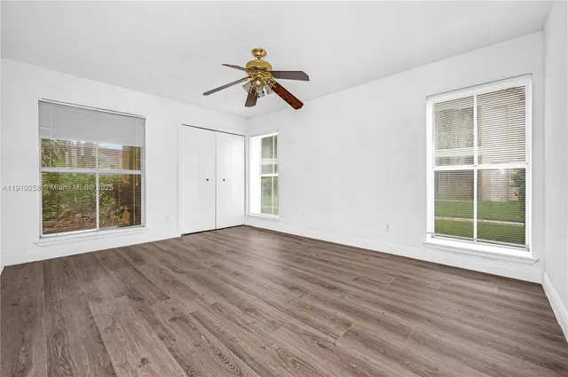 a view of empty room with wooden floor and fan