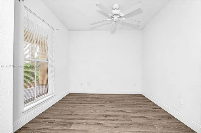 a view of a room with wooden floor and a ceiling fan