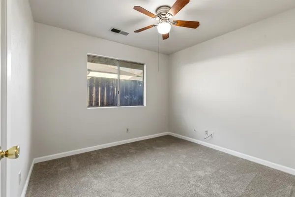an empty room with windows and fan