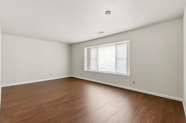 an empty room with wooden floor and window