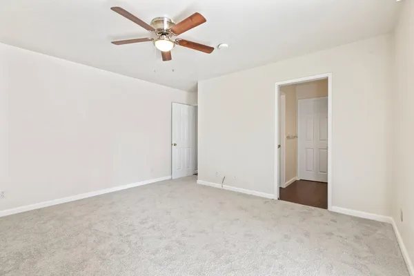 an empty room with ceiling fan and window