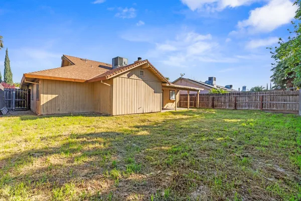 a view of a house with a yard and large trees