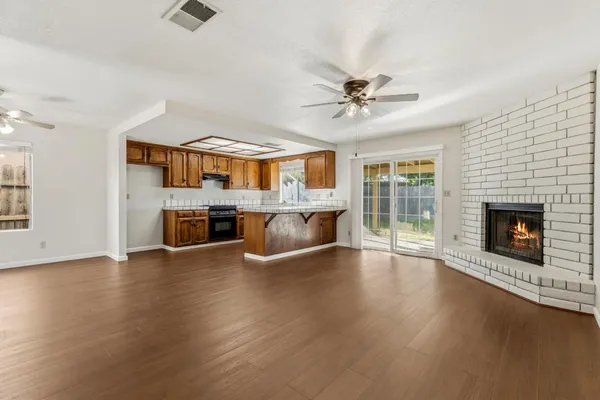 an empty room with windows fireplace and a kitchen view
