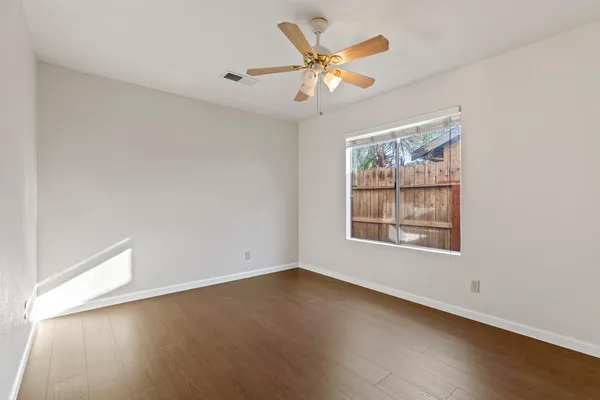an empty room with wooden floor and window