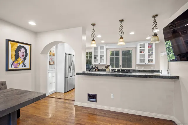 a view of a kitchen with kitchen island stainless steel appliances wooden floor and living room view