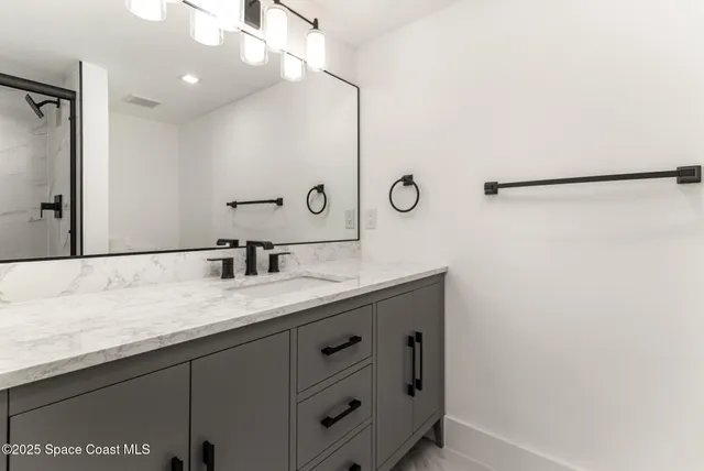 a bathroom with a granite countertop sink a mirror and shower