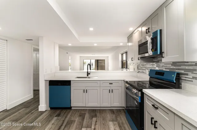 a kitchen with a sink dishwasher a stove and a refrigerator with wooden floor
