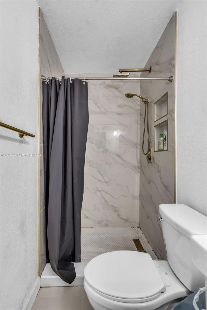 2761 Southwest 33rd Court Miami, FL 33133 - Photo 16 of 46 a white toilet sitting next to a shower curtain
