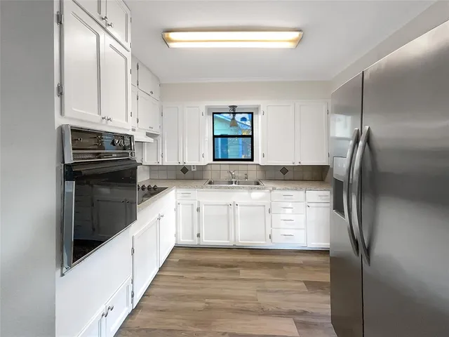 a kitchen with granite countertop white cabinets and stainless steel appliances