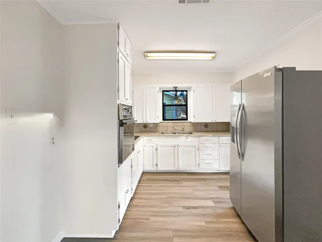 a large kitchen with a refrigerator and white cabinets
