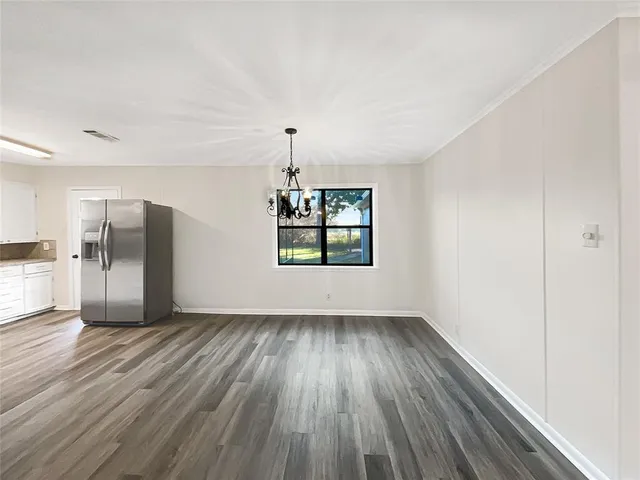 an empty room with wooden floor a ceiling fan and windows