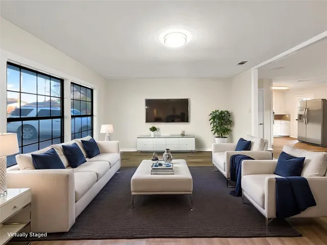 a living room with furniture flat screen tv and a large window