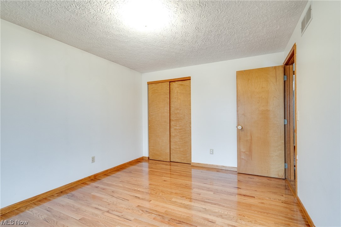 5303 Laubert Road Atwater, OH 44201 - Photo 25 of 37 Unfurnished bedroom with a closet, light wood-type flooring, and a textured ceiling