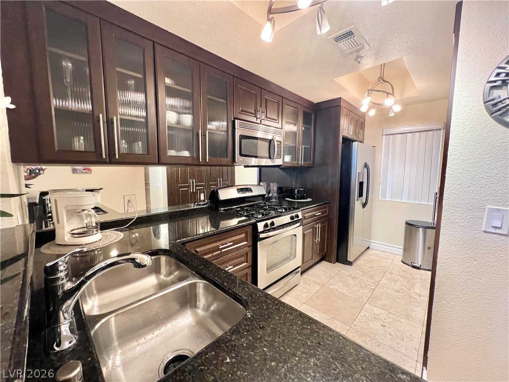 270 East Flamingo Road, Unit 313 Las Vegas, NV 89169 - Photo 5 of 27 A compact kitchen with dark cabinetry, granite countertops, and modern stainless steel appliances awaits culinary endeavors.