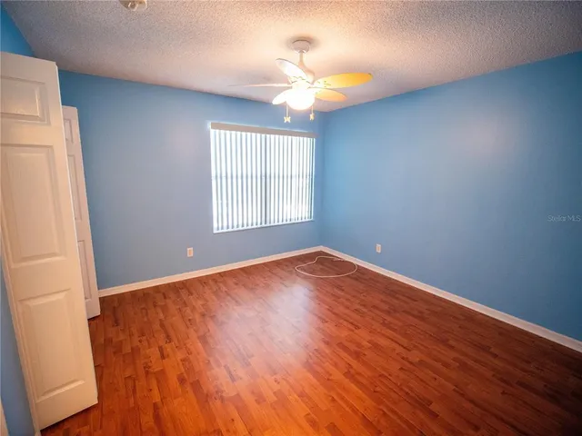 an empty room with wooden floor fan and windows