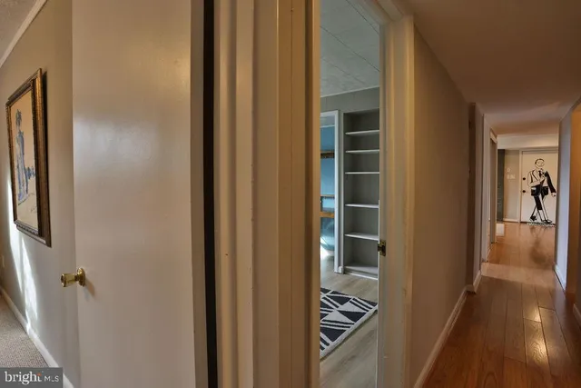 a view of a hallway with wooden floor and a living room