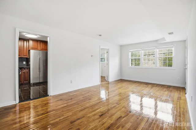 a view of empty room with wooden floor and window