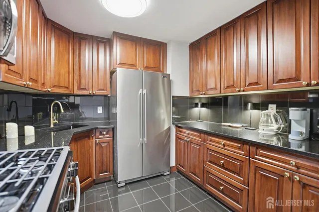 a kitchen with granite countertop a refrigerator stove and cabinets