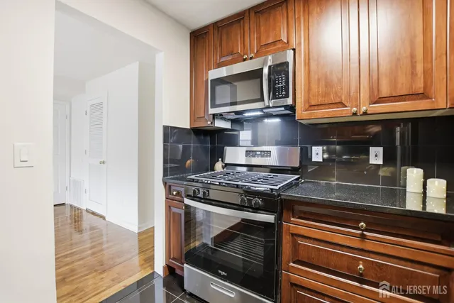 a kitchen with granite countertop a stove top oven microwave and cabinets