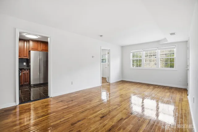 a view of empty room with wooden floor and window