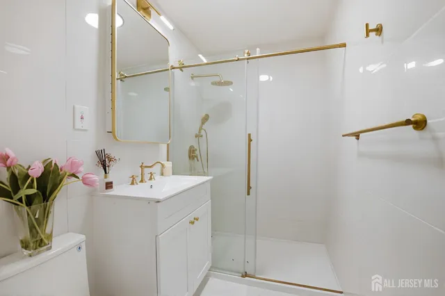 a bathroom with a sink a mirror a glass door shower and vanity