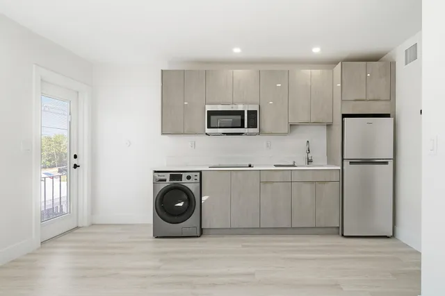 a kitchen with a sink a refrigerator and cabinets