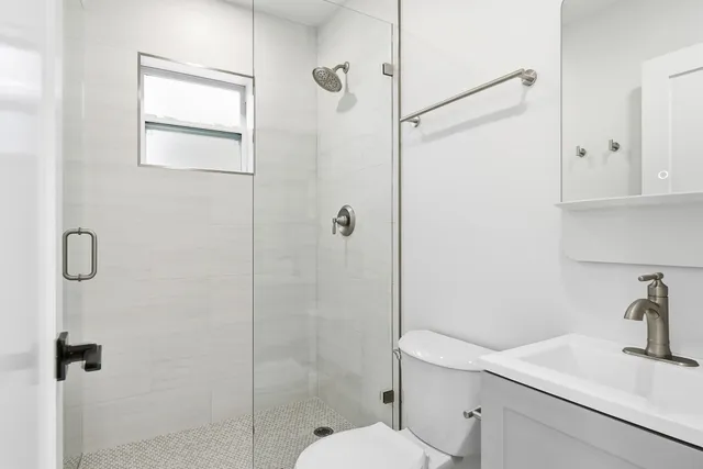 a bathroom with a shower sink vanity and toilet
