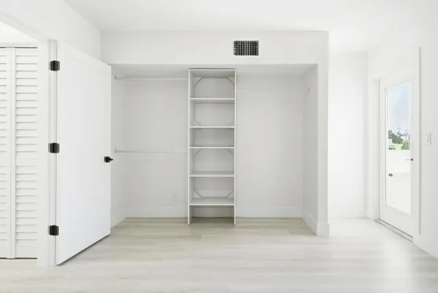 a view of an empty room with cabinet and window