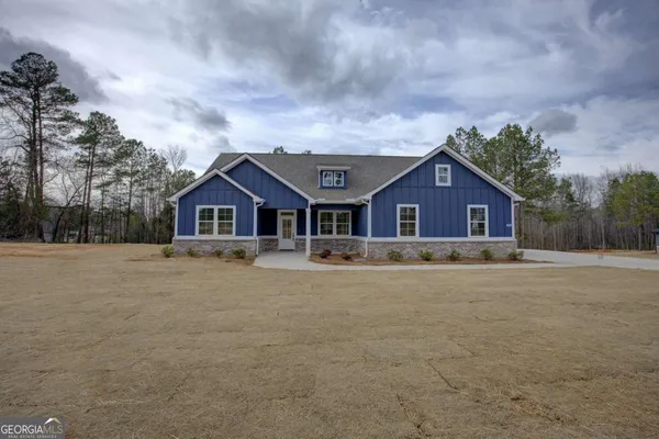 a front view of house with yard and trees in the background