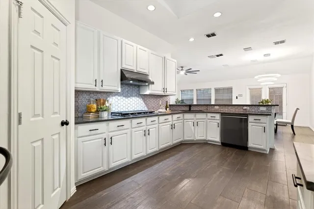 a large white kitchen with cabinets and wooden floor
