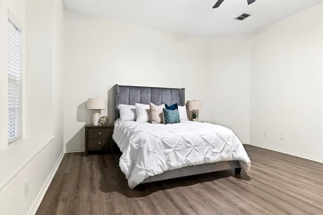 a bed sitting in a bedroom next to a window with wooden floor