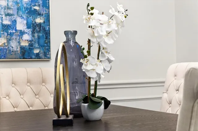 a vase of flowers sitting on a table with a mirror