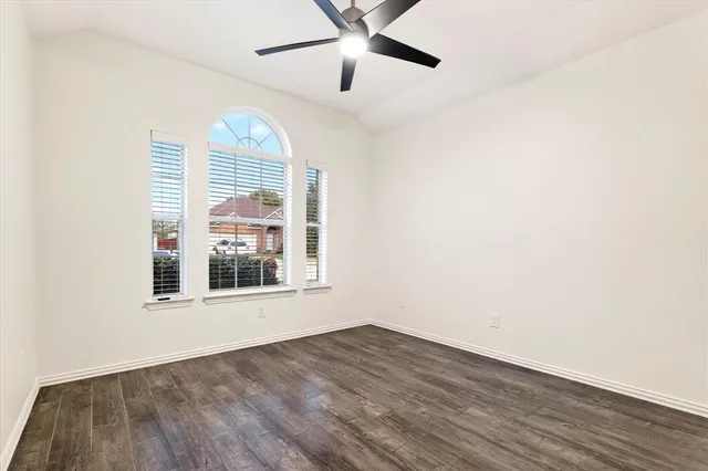 an empty room with wooden floor fan and windows
