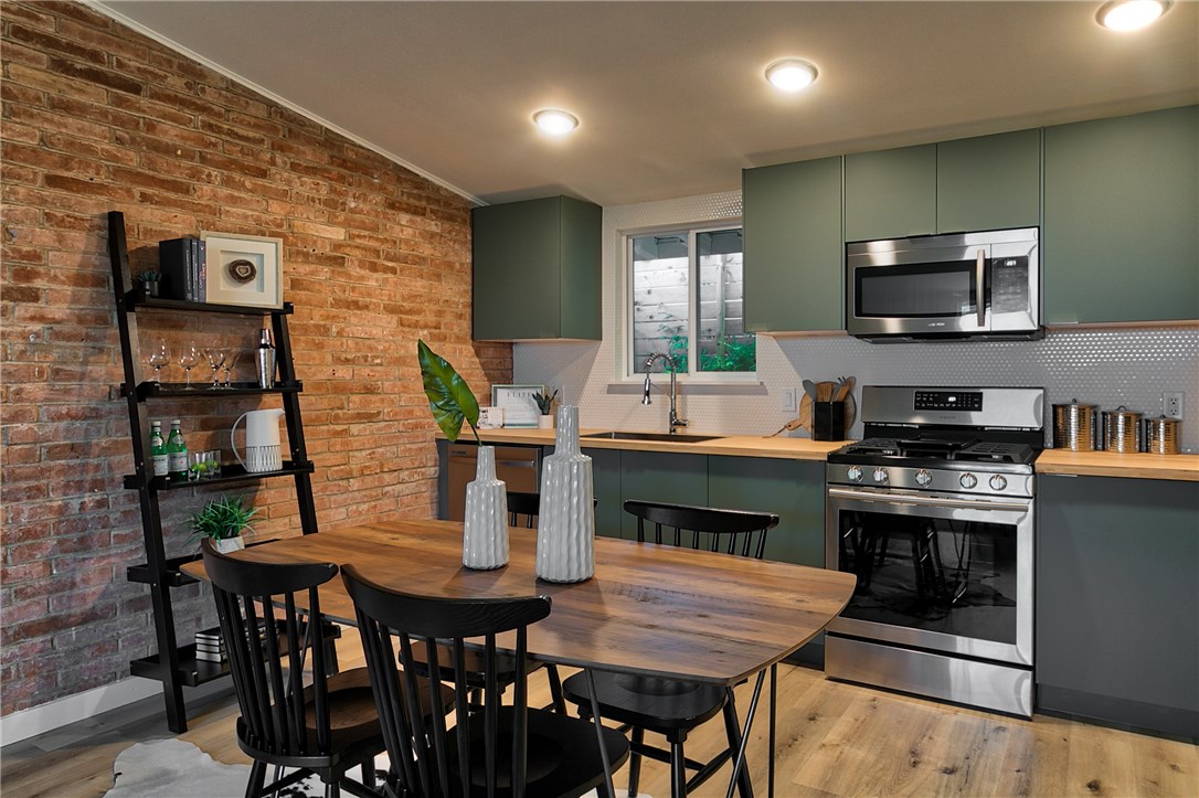 a open kitchen with stainless steel appliances granite countertop a stove a kitchen island a table and chairs