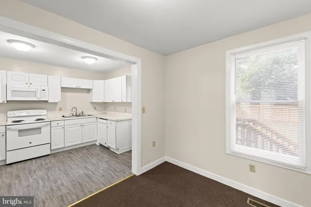 a kitchen with granite countertop white cabinets and white appliances