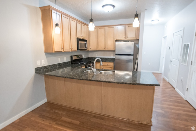 2150 South Main Street, Unit R405 Salt Lake City, UT 84115 - Photo 8 of 20 Kitchen featuring a peninsula with a dark countertop, stainless steel appliances, wood-finish flooring, and pendant lighting
