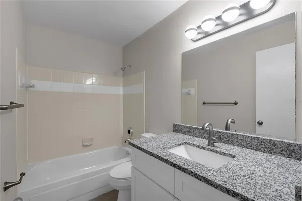 a bathroom with a granite countertop bathtub a sink and mirror