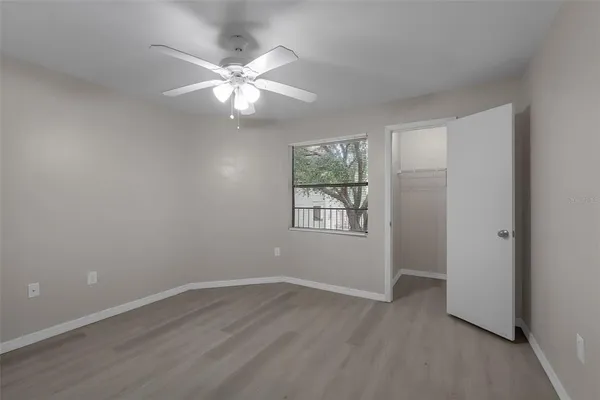an empty room with wooden floor fan and windows
