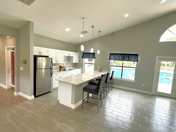 a kitchen with stainless steel appliances a dining table chairs refrigerator and sink