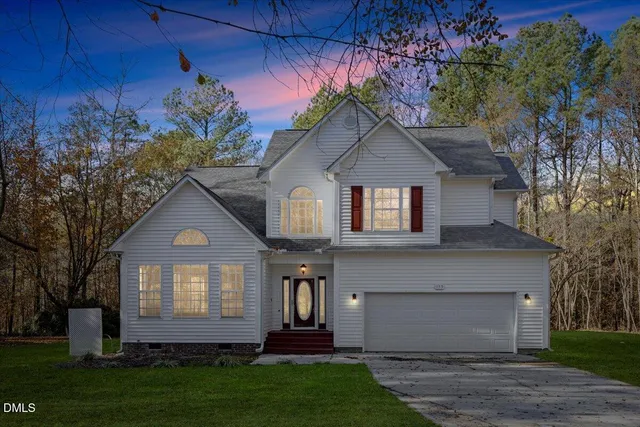 a front view of a house with a garden and trees