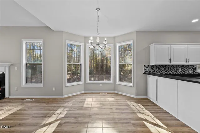 a view of an empty room with window and chandelier