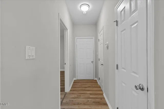 a view of a hallway with wooden floor and a bathroom