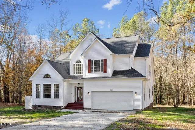 a view of a house with a yard and large tree