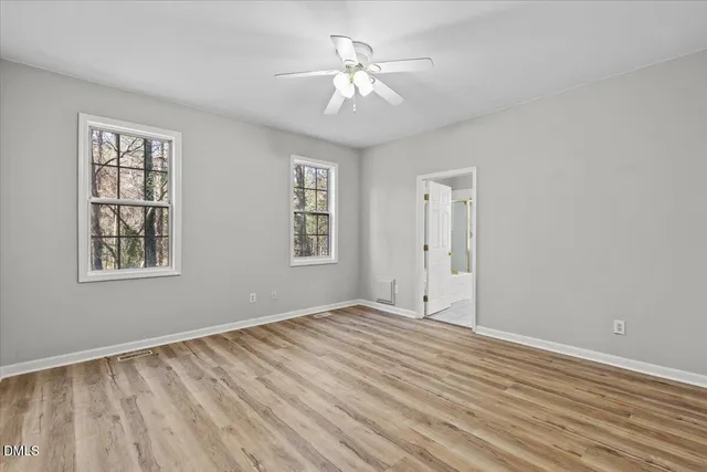 a view of an empty room with a window and a chandelier fan