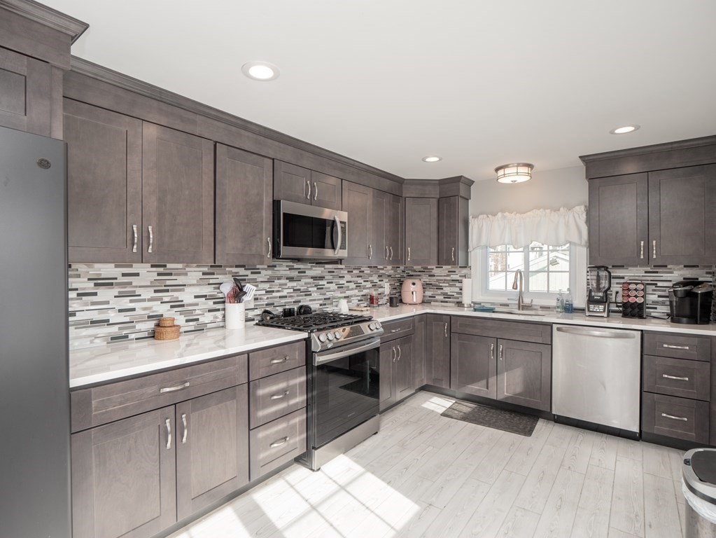 a kitchen with kitchen island granite countertop appliances cabinets and a sink