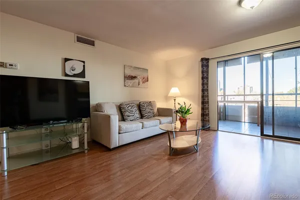 a living room with furniture a flat screen tv and wooden floor